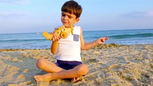 小男孩在沙滩上玩玩具飞机视频