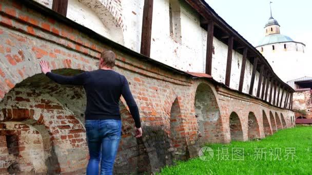 Tourist touches the historical reference massive brick walls of 