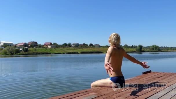 金发碧眼的人坐在湖边木桥视频