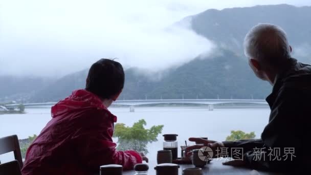 亚洲高级夫妇喝茶美丽雨天山与湖查看