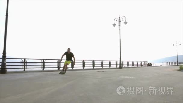 运动的年轻人滚轴溜冰在夏季海滨