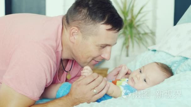 Young father playing with his son two months. he smiles