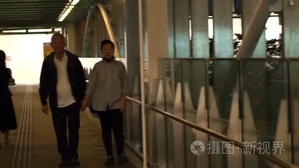 亚洲高级退休的夫妇手牵着手沿着盖走道从火车站走到公寓