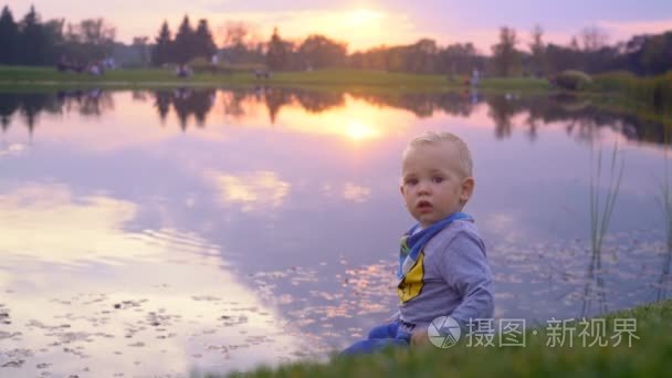 一个小男孩坐在湖边，看日落视频