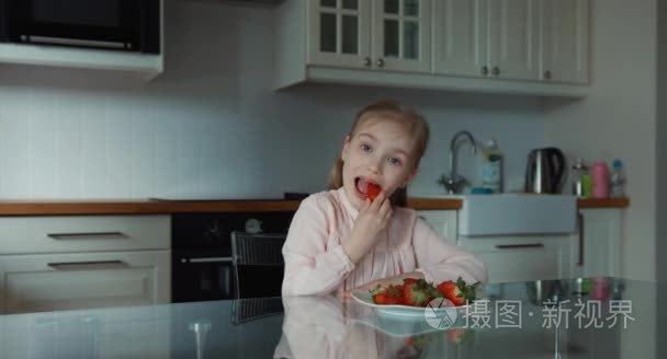 孩子吃一个大红色的草莓，看着相机。还行