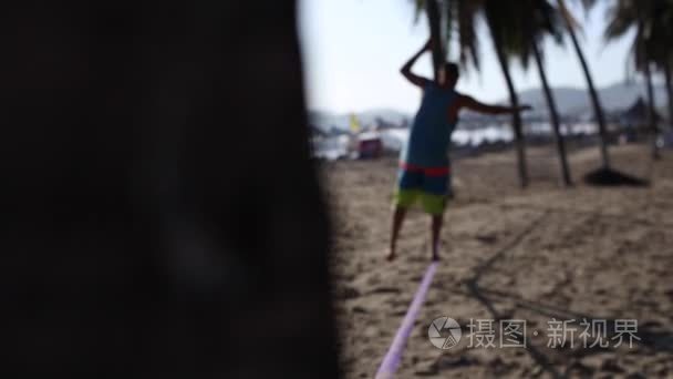 男人在松绳在海滩上保持平衡视频