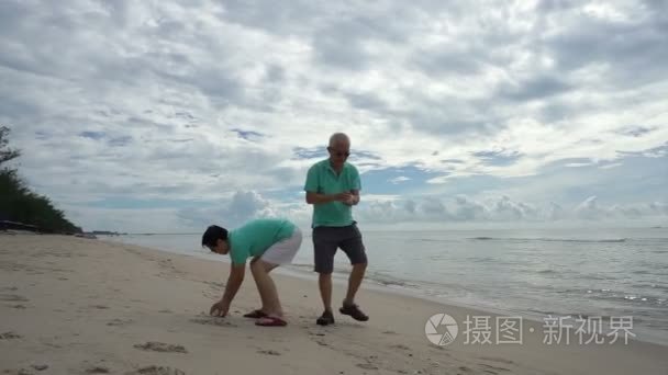 亚洲对老年夫妇在海滩上捡贝壳