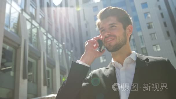 年轻的沉思商人谈在户外的电话视频