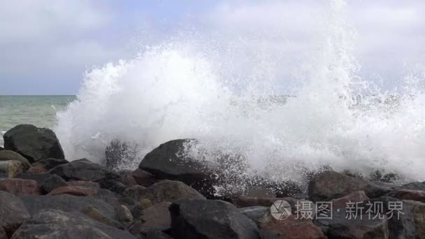 喷雾剂在岩石的海滩上冲浪。慢动作