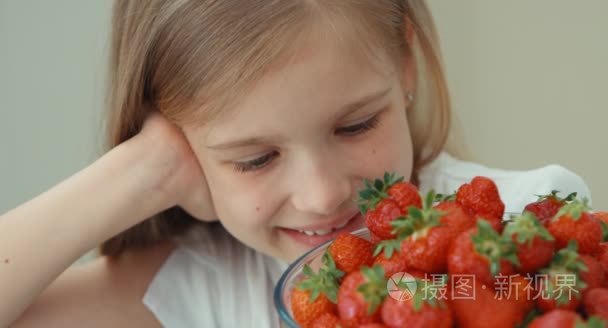 极端的肖像女孩拥抱大盘子里的草莓和嘲笑的相机。顶视图