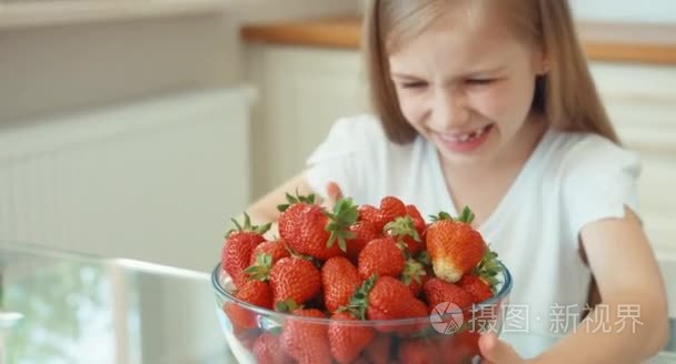 孩子搓他的手。草莓一大盘的女孩。女孩看着相机