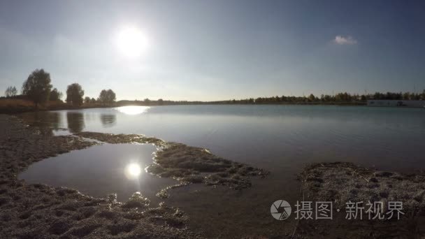 与太阳倒影的水体与圆石滩湖视频