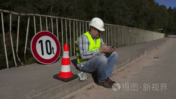 道路建筑工人坐在和使用平板电脑