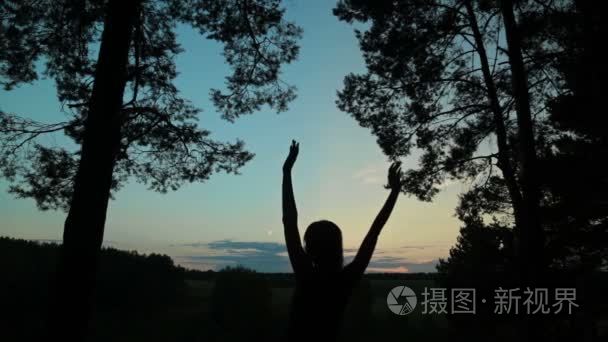 天空的幸福的年轻女人剪影在空气中举起手