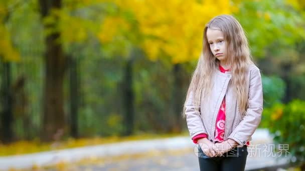 悲伤的小女孩，在秋天看着相机和微笑的画像