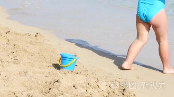 在蓝色泳装沙滩上玩耍的小女孩