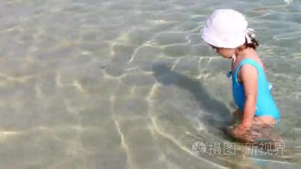 在蓝色泳装沙滩上玩耍的小女孩视频