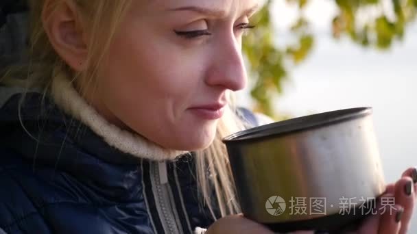 金发女郎正在从一个热水瓶喝茶视频