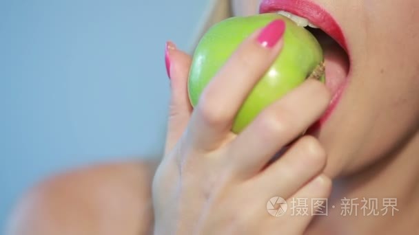 漂亮的女孩吃蓝绿色的苹果。特写