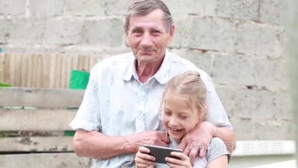 爷爷和孙女玩游戏对你的手机在户外夏季的一天