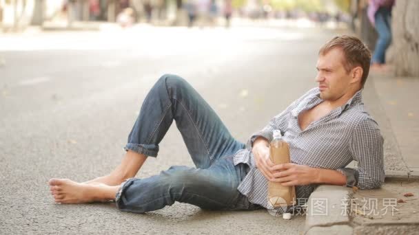 喝醉了的人躺在外面的人行道上。从一个纸袋喝啤酒的人