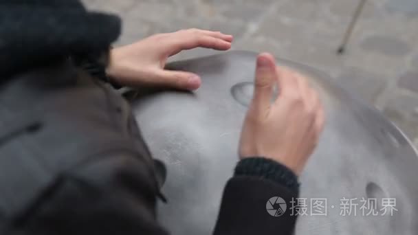 青年街头艺术家在街上表演。表演者与 Handpan 或挂起，是一个传统的民族鼓乐器手关闭了