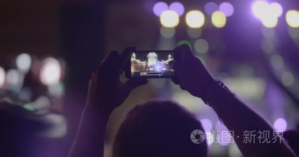 观众人在室外音乐会使舞台聚光灯通过智能手机全景照片