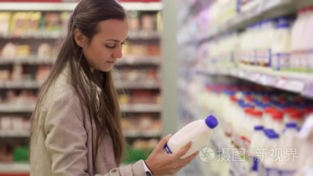 年轻女子在超市选择一瓶牛奶乳品部
