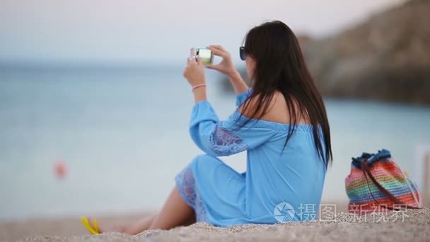 年轻女子在晚会滩上的手机拍照视频