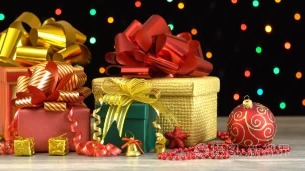 美丽的圣诞礼品盒和反对多彩闪烁花环在黑色背景上的木地板上的装饰品。无缝 loopable