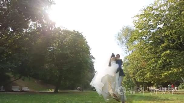 新娘和新郎在一个阳光明媚的公园拥抱了彼此