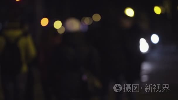 慢动作模糊画面的人走在夜晚的城市的街道，行人等待走在一个十字路口