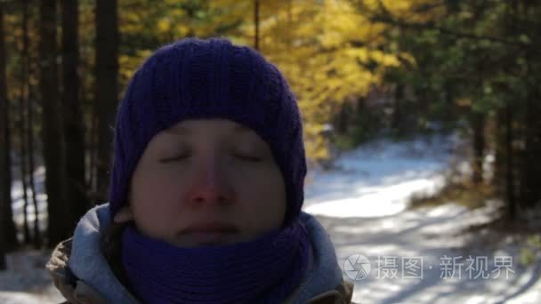 一名年轻女子在下雪的冬天的森林里沉思在晴朗的一天