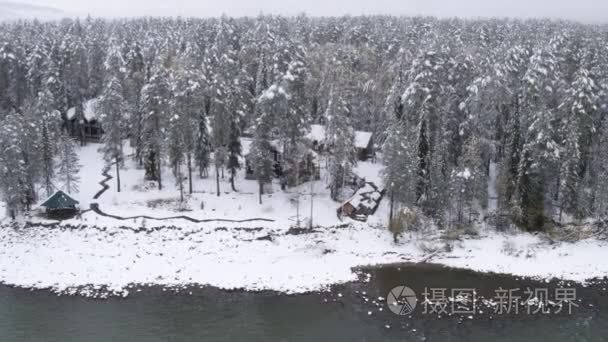 鸟瞰图。房子在冬天的树林。白雪皑皑的丛林上空飞行。在冬天的性质。景观全景。西伯利亚的阿尔泰山，