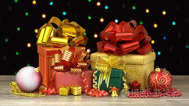 美丽的圣诞礼品盒和反对多彩闪烁花环在黑色背景上的木地板上的装饰品。无缝 loopable