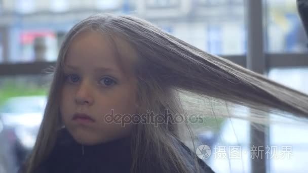 美容师干金发的毛孩子是客户端美发沙龙发型师正在理发的小女孩坐在黑闲荡与严肃的面孔