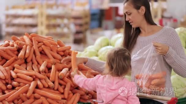 母亲和女儿选择蔬菜时在超市购买食品杂货