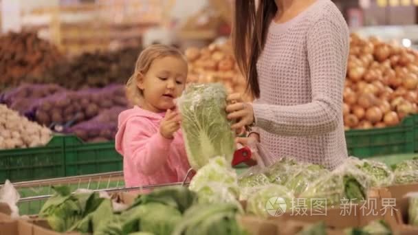 母亲和女儿选择蔬菜时在超市购买食品杂货