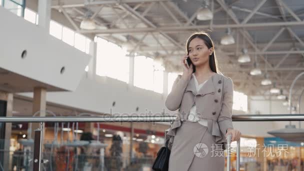 一个十几岁的年轻游客女人来访的商城购物使用她的智能手机设备和微笑的画像。女商人，在机场