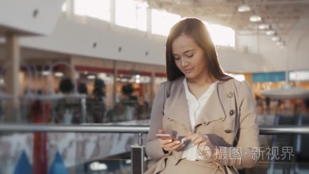 一个十几岁的年轻游客女人来访的商城购物使用她的智能手机设备和微笑的画像。在机场上 suset 的女商人