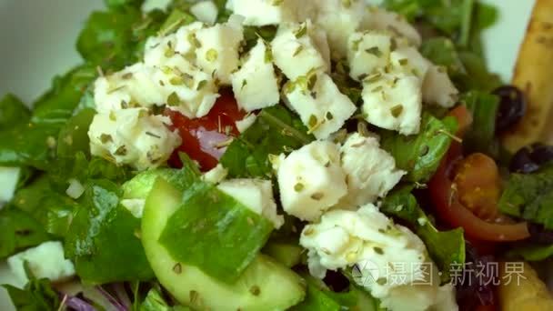 希腊沙拉配新鲜蔬菜，奶酪和黑橄榄。健康的新鲜素食食品。旋转镜头