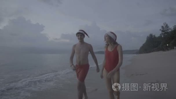 夫妇在海滩上穿圣诞老人的帽子视频