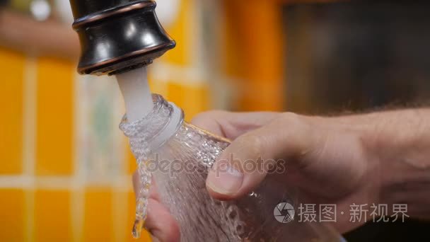 一个男人笔芯塑料一瓶水与自来水从水龙头高速快门