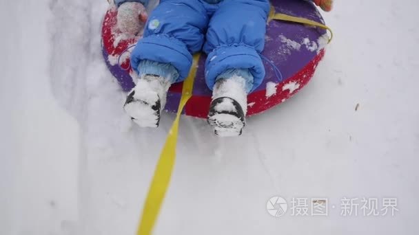 一个快乐的孩子骑在 snowtube 上的多雪小山