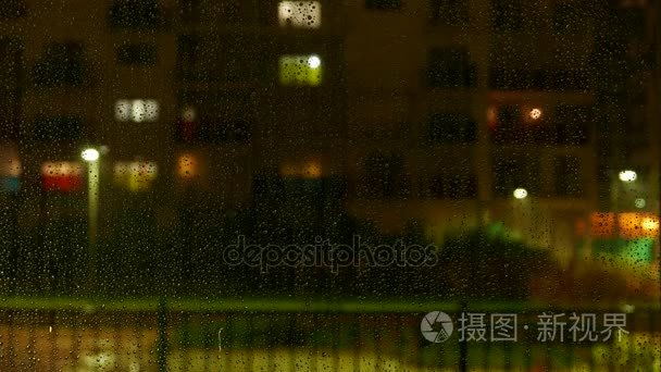 水滴在窗口外面在下雨时。散焦的高层建筑与橱窗照明和活动的背景。时间流逝 4 k 视频