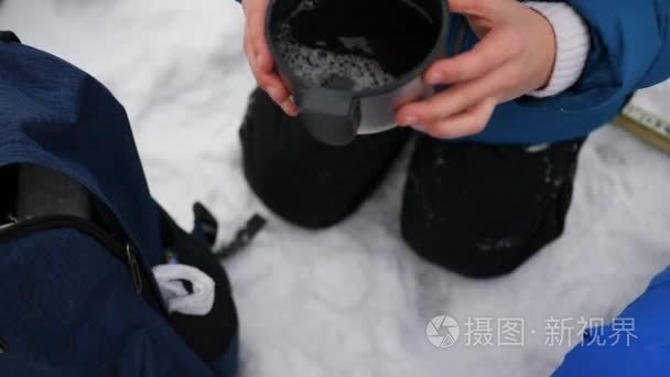 在冬天室外孩子从一大杯喝热茶。溜冰场