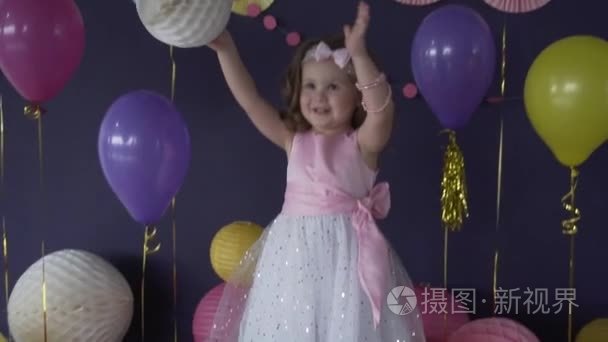 漂亮的小宝贝女孩笑和玩气球在她的生日聚会上