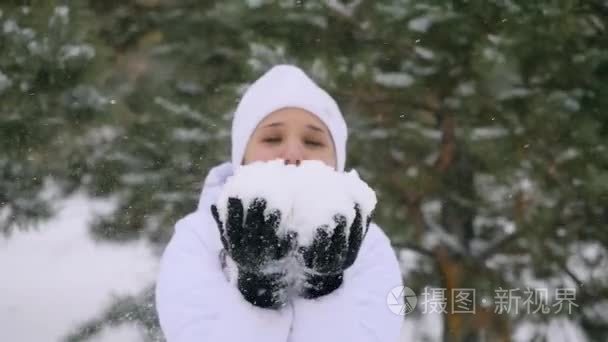 在享受冬天的时候在慢动作的降雪吹雪花的年轻女人。1920 x 1080