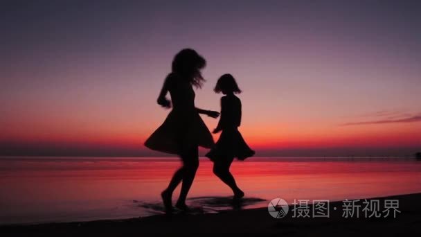 两个女孩在海滩上飞舞的日落视频