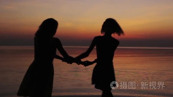 两个女孩在海滩上飞舞的日落视频